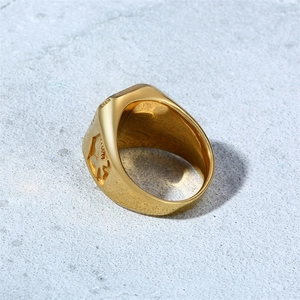 Vue détaillée de la bague en acier doré avec motif de croix en relief sur le côté