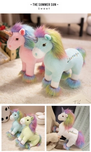 Detail view of plush unicorn toys in pastel pink and blue with embroidered courage text