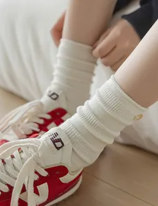 Detail of cream rib-knit mid-calf socks featuring a decorative button and soft texture