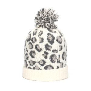 Detail of winter leopard knit beanie with soft grey pompom and thick woven texture