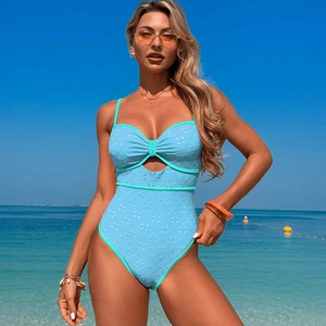 Light blue one-piece swimsuit with embroidery and cut-out details on a sunny beach