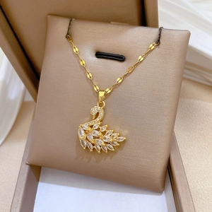 Macro shot of gold swan pendant necklace with clear cubic zirconia in a beige jewelry box