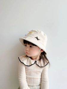 Detailed view of children's beige sun hat with colorful bow and knit top with ruffled collar