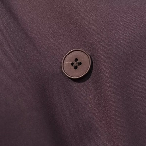Détail macro d'un bouton marron à quatre trous sur un tissu en sergé violet