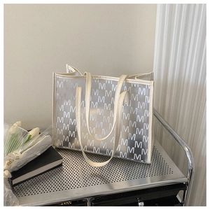 Macro detail of transparent frosted tote bag with letter M patterns on metal shelf