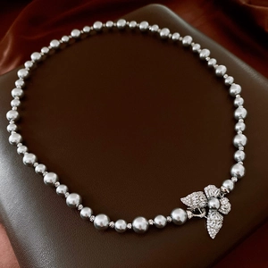 Détail macro d'un collier de perles grises avec un fermoir fleur en zircon scintillant