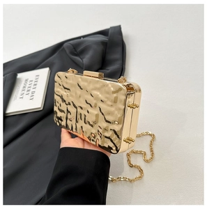 Detail of a gold hammered metal evening clutch bag with elegant chain strap and clasp