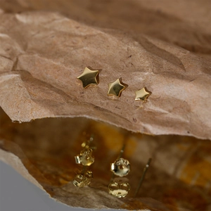 Three-piece set of gold star stud earrings in small to large sizes on textured paper