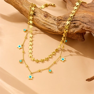 Detail of double-layer gold star necklace with blue turquoise and evil eye pendant on wood