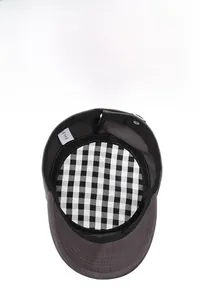 Detail of dark gray flat cap featuring black and white plaid lining and quality stitching
