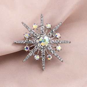 Silver snowflake brooch with sparkling crystals on soft fabric background