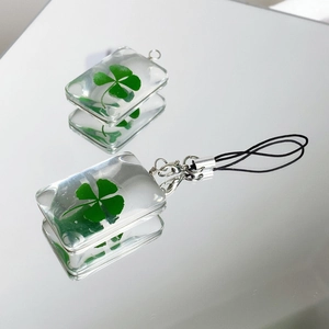 Natural four leaf clover pendant in a clear resin rectangle with a black cord