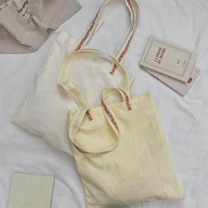 Détail de broderie florale sur les larges bretelles de sacs fourre-tout en toile