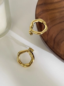 Macro view of gold irregular geometric round earrings with high-gloss polished metal surface