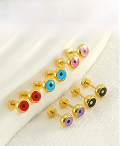 Détail de boucles d'oreilles œil porte-bonheur avec fermoirs à vis dorés sécurisés