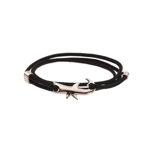 Detailed view of black braided cord bracelet with a silver shark-shaped metal pendant