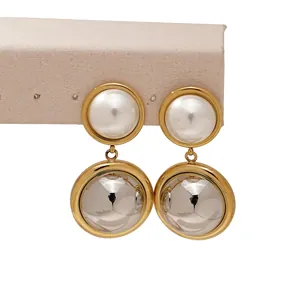 Vue macro de boucles d'oreilles en acier bicolore avec perle et sphère métallique
