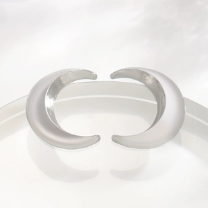 Detailed view of crescent moon silver earrings on a clear acrylic stand in bright light