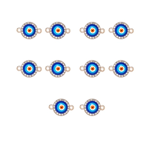 Close-up of golden alloy evil eye connectors with blue enamel and rhinestones on white background