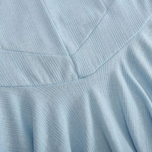 Detailed macro of light blue knit fabric with hollow diamond patterns and rib textures