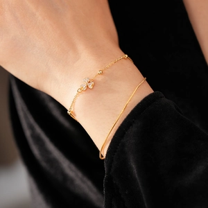 Detail eines vergoldeten Kleeblatt-Armbands mit Zirkonia und eleganter Schlangenkette