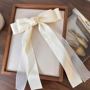 Dettaglio del grande fiocco in tulle crema con nastri su un elegante supporto in legno