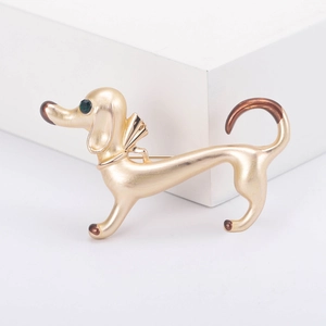 Golden dachshund brooch with green gemstone eyes on white minimalist background