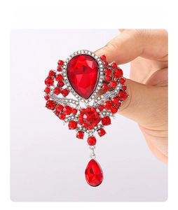 Macro detail of luxury vintage brooch with red crystal teardrop pendant and silver base