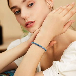 Close-up of dual-layered tennis bracelets with blue zircon stones on a model wrist