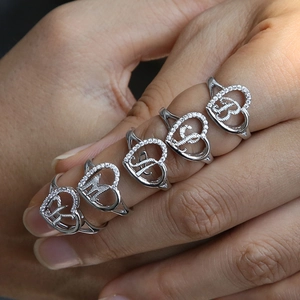 Close-up of five silver heart-shaped rings with sparkling crystals and cursiv letters