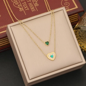 Macro shot of double-layer gold necklace featuring emerald green heart pendants
