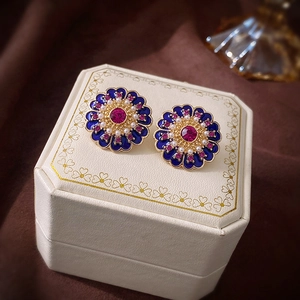 Macro shot of vintage floral earrings with blue enamel, pearls, and red zircon crystal