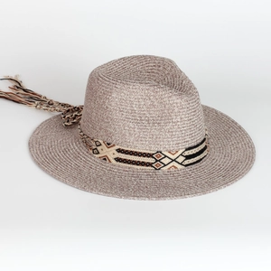 Detail of bohemian straw fedora hat featuring geometric woven band and long tassel accents