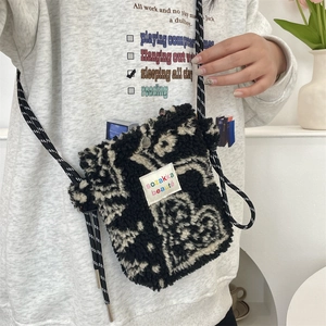 Detail of plush black and white textured crossbody bag with woven rope strap on a model