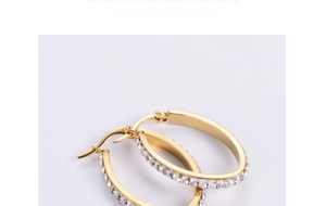 Macro shot of gold-plated egg-shaped hoop earrings with sparkling inlaid rhinestones