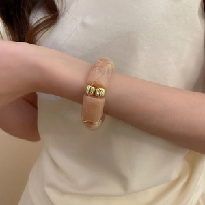 Detail view of peach pink resin beads and gold metal spacers on a modern beaded bracelet