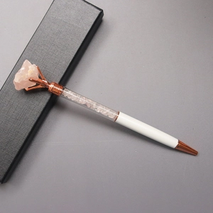 Detail of a white metal pen with pink crystal fragments and raw stone top in a gift box