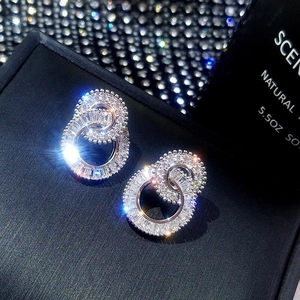 Macro shot of silver butterfly stud earrings with nested double rings and shiny zircon