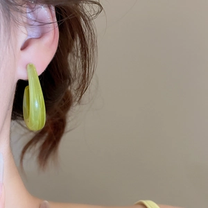 Gros plan d'un mannequin portant des boucles d'oreilles créoles en résine vert clair