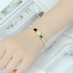 Elegante bracciale rigido dorato a cuore con intarsio nero e diamanti luccicanti