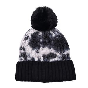 Close-up of black and white tie-dye knit hat with black faux fur pompom and ribbed cuff