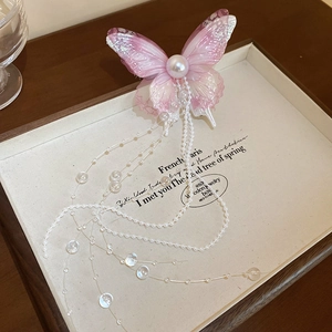 Detail showing pink butterfly hair clip with mesh wings, large pearl and flowing tassels