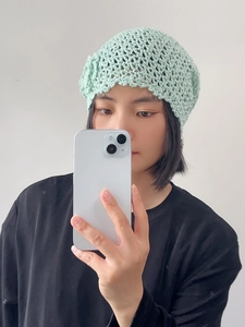 Detail of mint green crochet sun hat with delicate openwork mesh and floral accent