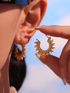 Detail of 18k gold plated sunflower stud earrings shown on ear with blue sky background