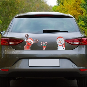 Close-up of festive reindeer and snowman magnetic stickers on a car rear window
