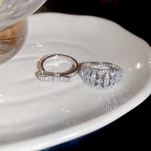 Macro detail of silver bow ring and openwork band set with sparkling zircon stones