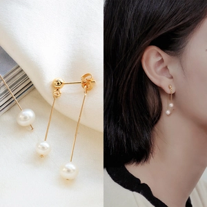 Detail of elegant gold drop earrings featuring natural freshwater pearls and minimalist metal bars
