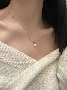Close-up of a s925 silver rope knot necklace with a white teardrop pearl pendant on a model