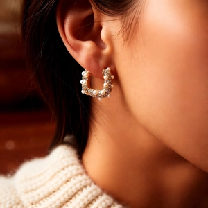 Vue détaillée d'une boucle d'oreille en or en U avec perles blanches et cristaux brillants