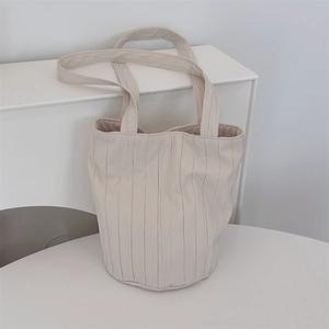 Vista detallada del bolso tote plisado crema con textura de acordeón y base redonda
